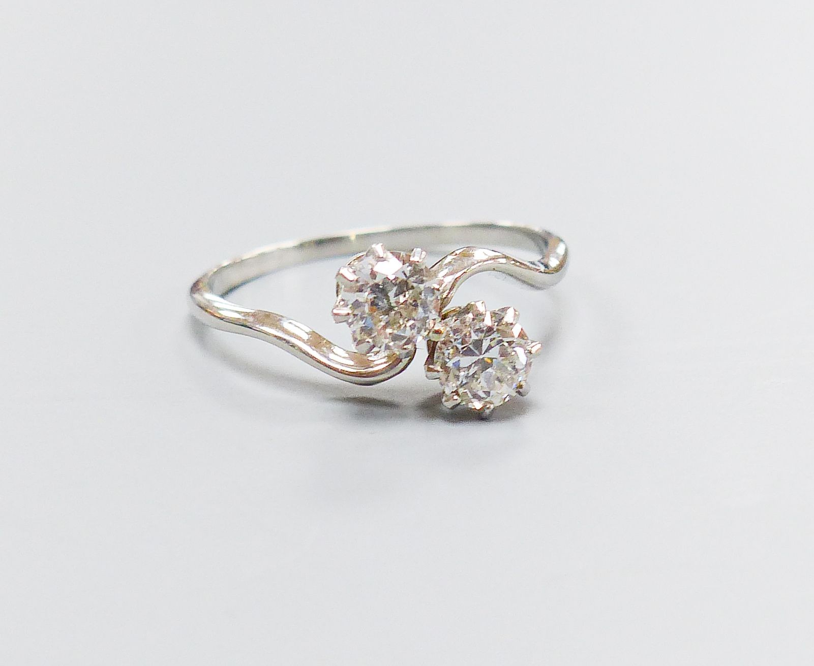 A white metal and two stone diamond set crossover ring, size K, gross 2.4 grams